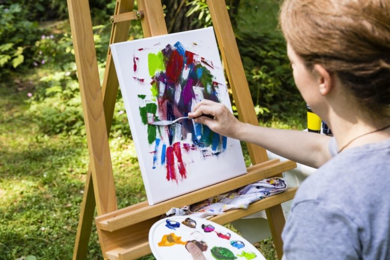 woman painting at a canvas with palette knife