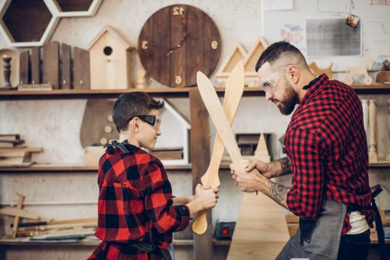 father and son playing with wooden swords