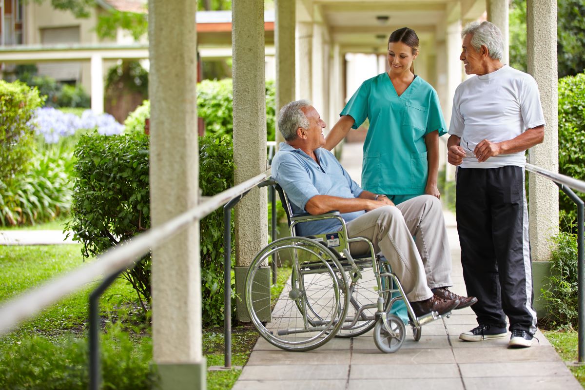 a senior citizen in a wheel chair talking to a nurse and another senior