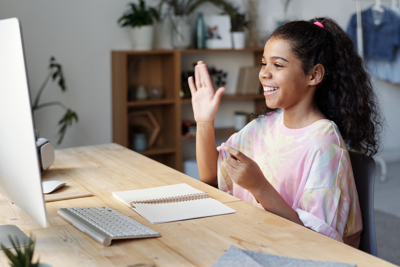 young girl raising hand during online class