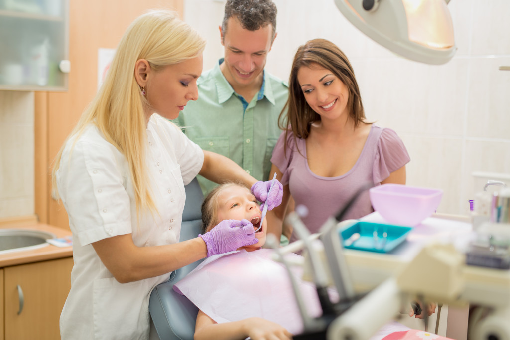 A kid being checked by a dentist with parents watching