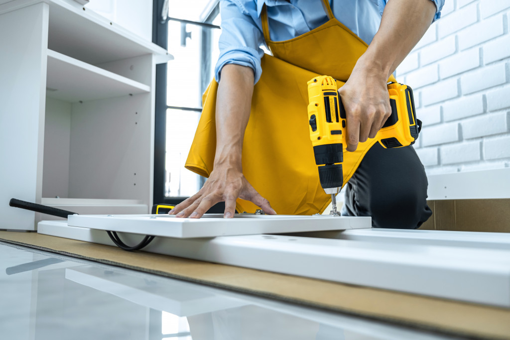 Professional using a drill on wood inside a house.