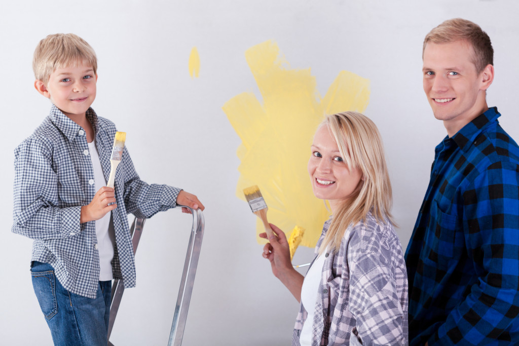 a family painting wall with little boy and mother and father