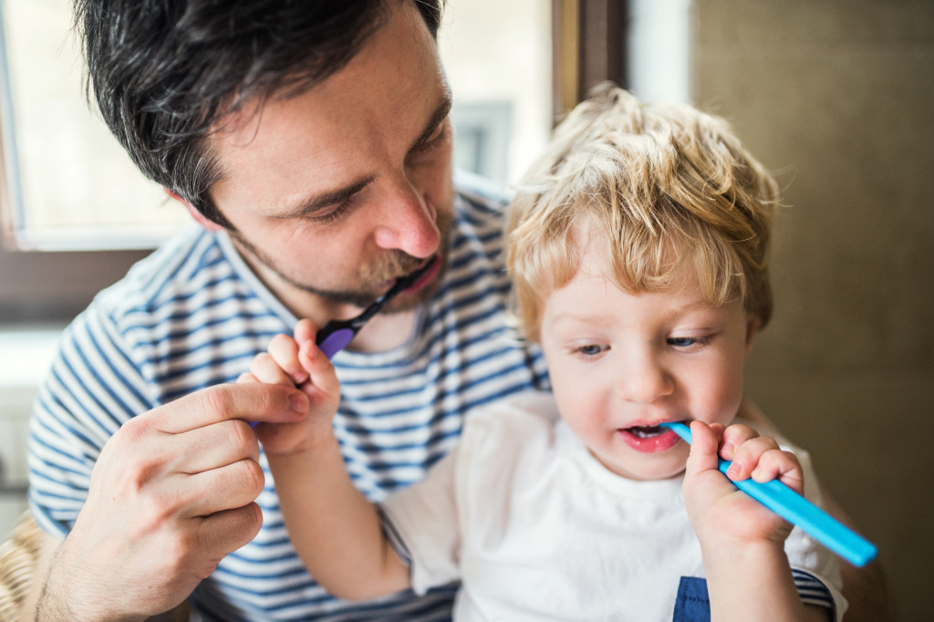 A father and toddler brushing their teeth