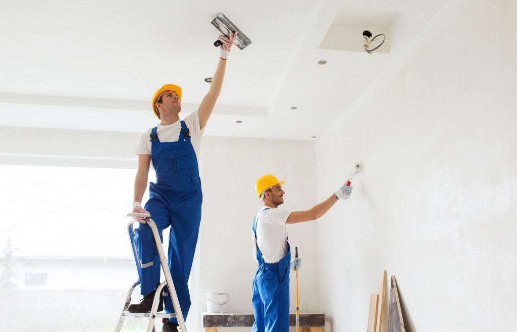 two male contractors painting the walls of the house white