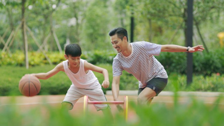 dad and son playing basketball outdoors