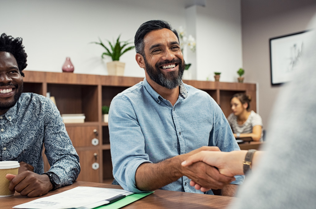 happy male boss shaking hands in a modern office