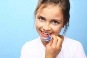 girl holding a retainer for her teeth