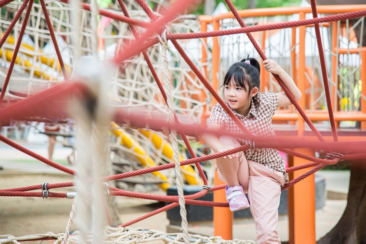 A little girl playing at an obstacle course