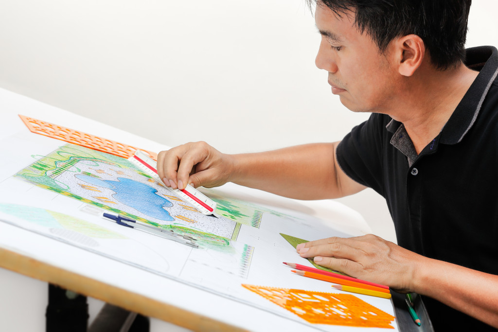 man sketching and measuring the plan for a garden