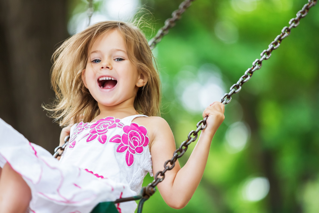 happy young girl sitting in swing in their backyard