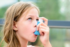 female child with asthma using inhaler