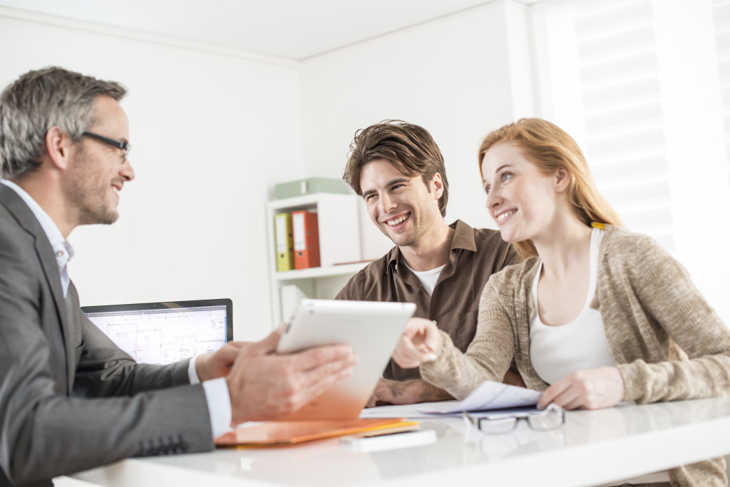 couple discussing with a male real estate agent in his office