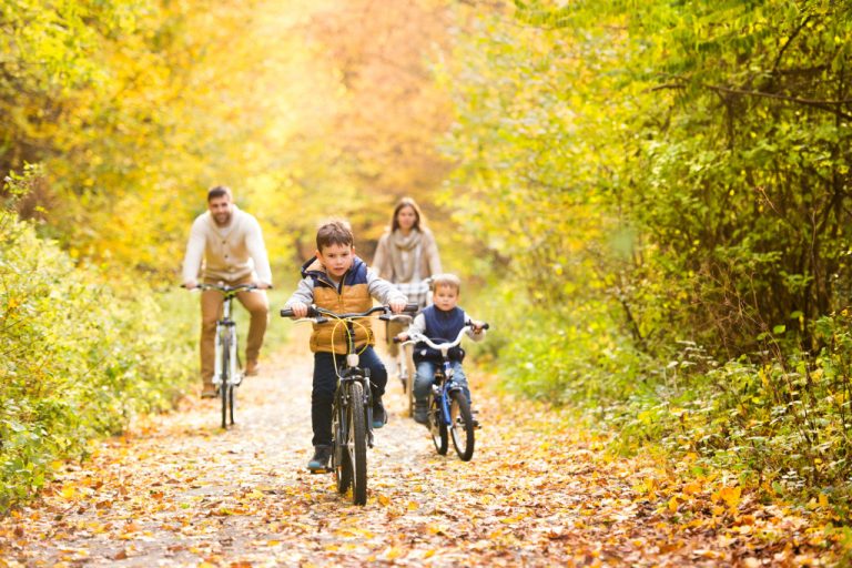 Family going on a bike ride in the park during autumn.