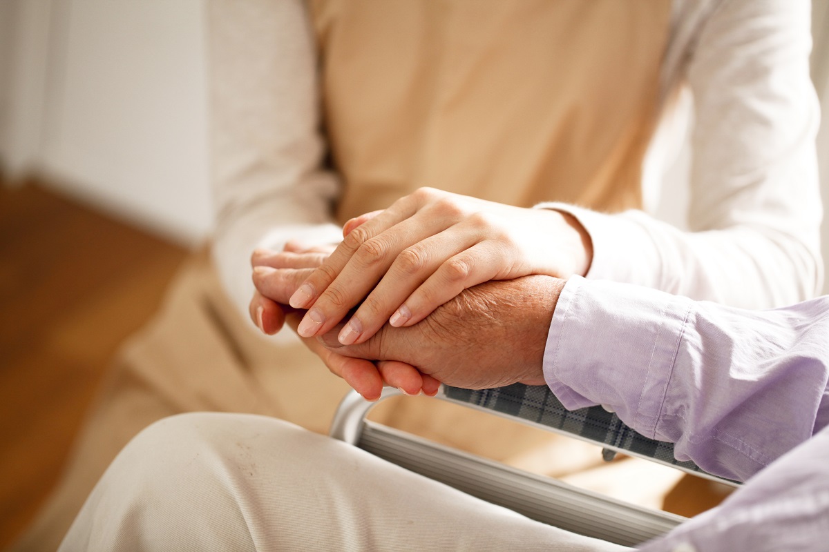 man in hospice and wheelchair being held by younger woman