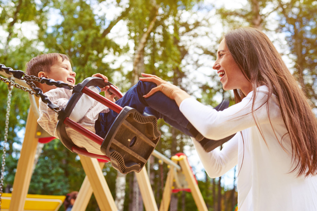 woman happily playing with son in swing